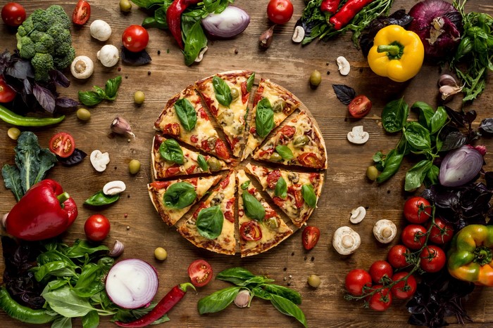 Pizza and fresh vegetables on a wooden table