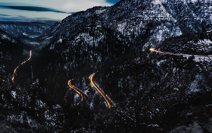 Light trails on a snowy mountain road at dusk