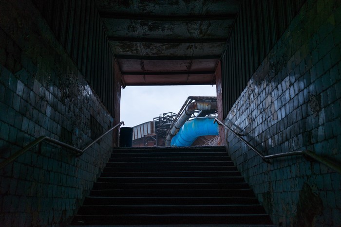 Stairs leading to industrial complex with blue pipe