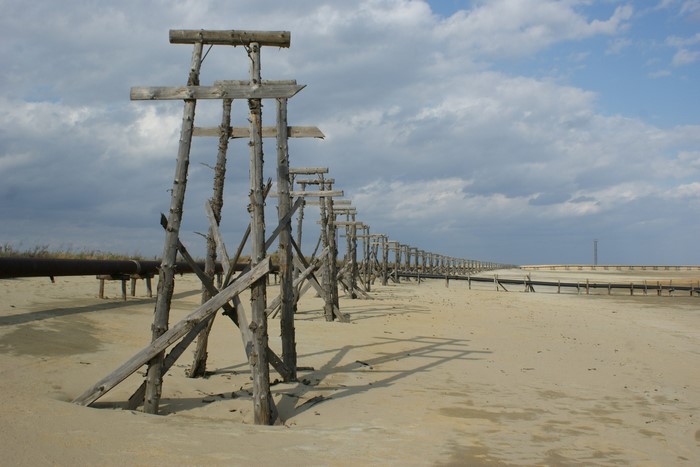 Wooden structures and pipeline in sandy landscape