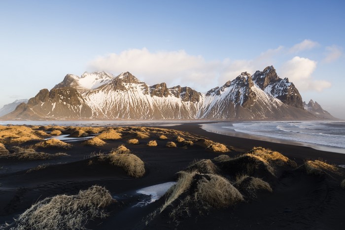 Snow-capped mountains on a black sand beach