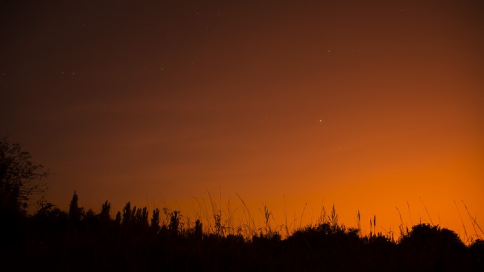 Stars over a silhouetted landscape at sunset