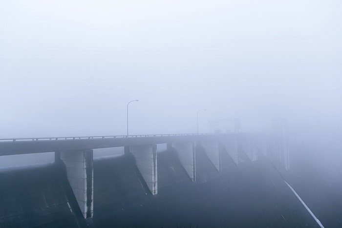 Bridge over a dam in mist