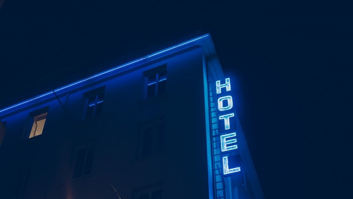Blue neon HOTEL sign on a building at night