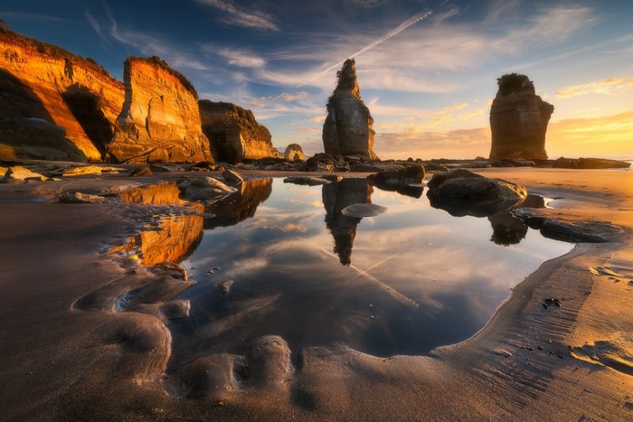 Coastal cliffs and rock formations at sunset with reflection