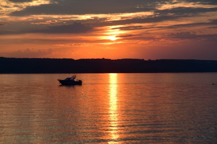 Boat on water during sunset with orange sky