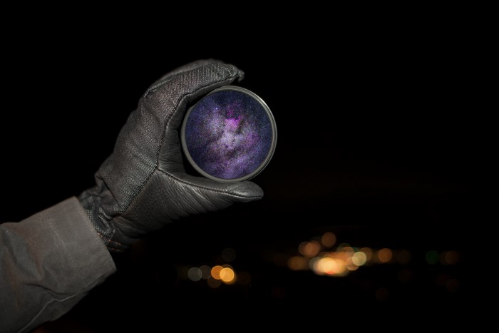Gloved hand holding a lens with galaxy