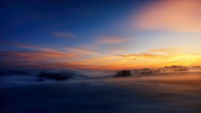 Winter sunrise over misty fields