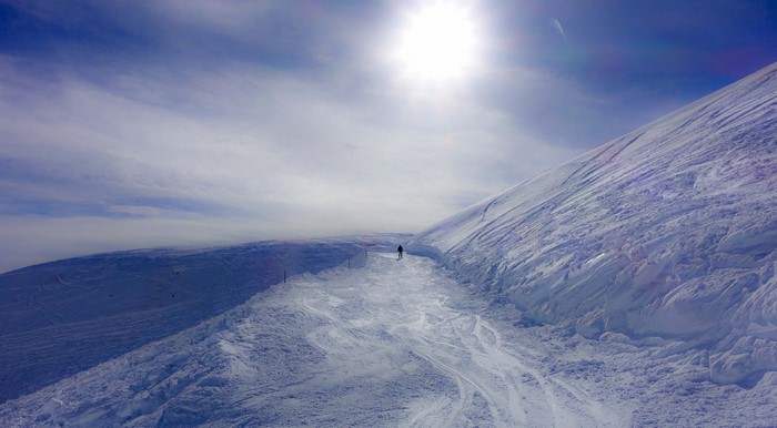 Skier on a snowy mountain slope under a bright sun