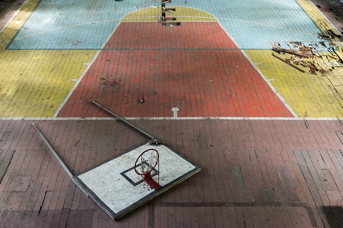 Abandoned basketball court with broken hoop