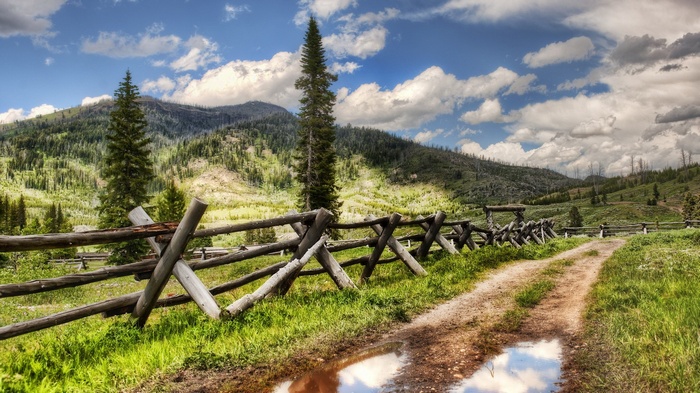 Dirt road and wooden fence in a mountain landscape