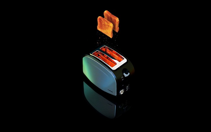 Toaster with toast popping out on black background
