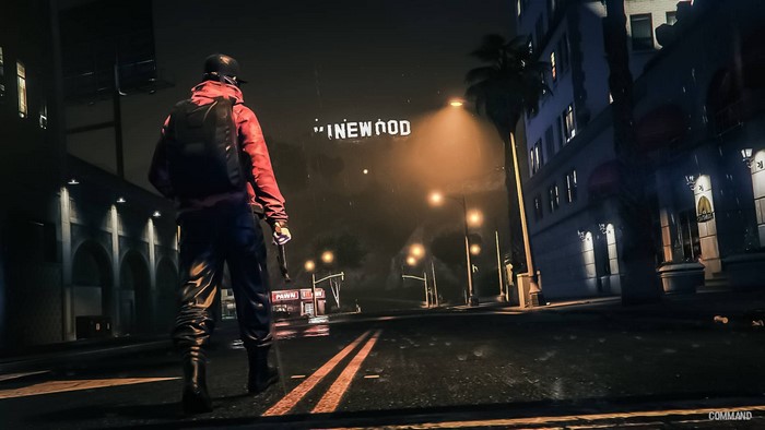 Man in red jacket in front of Hollywood sign at night