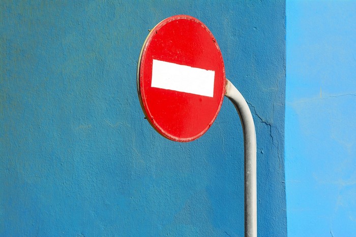 Red and white no entry sign on blue wall