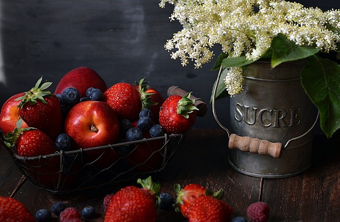 Basket of strawberries, apples, blueberries, and flowers