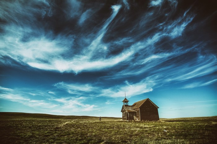 Abandoned church on a grassy plain under a cloudy sky