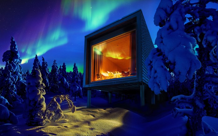 Modern cabin under Aurora Borealis in snowy Finland