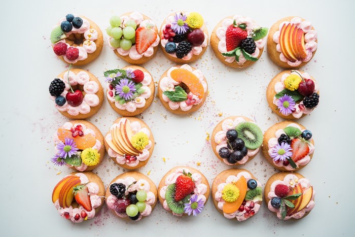 Assortment of decorated donuts with fresh fruit and flowers