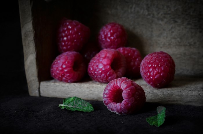 Raspberries and mint leaves in a wooden crate