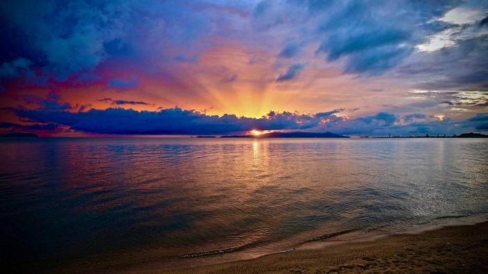Sunset over the sea with colorful clouds and beach