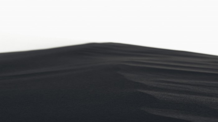 Black sand dunes against a white sky