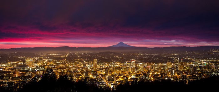 Cityscape at dusk with snow-capped mountain in background