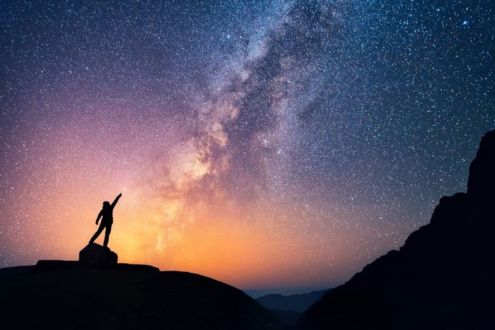 Silhouette of a person reaching for the Milky Way
