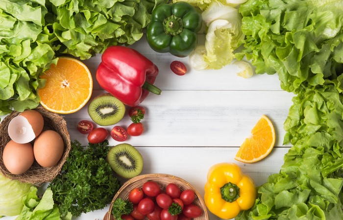 Fresh vegetables, fruits, and eggs on a white wooden table