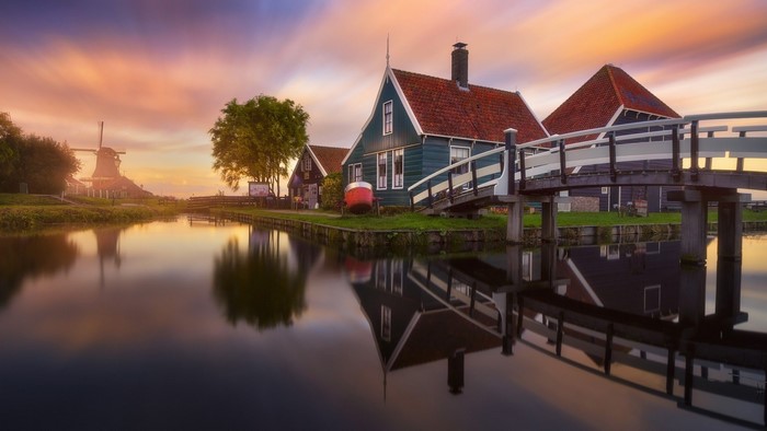 Village with windmill and bridge at sunset with reflection