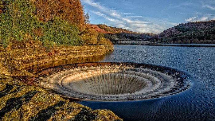 Circular overflow drain in a reservoir with hills in the background