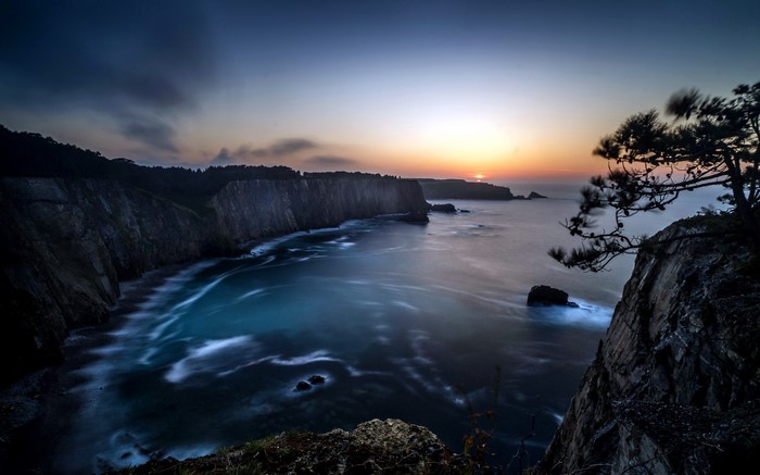 Sunset over rugged cliffs and sea with long exposure