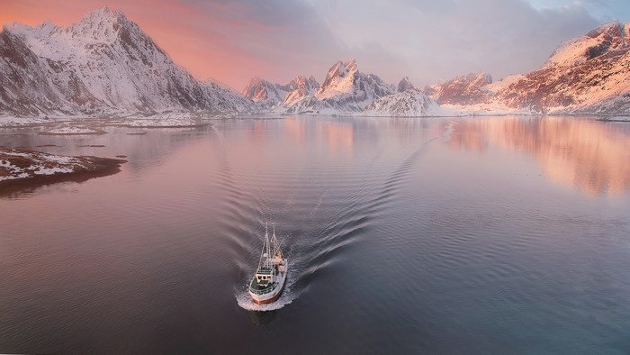 Fishing boat sailing in Lofoten, Norway during sunset