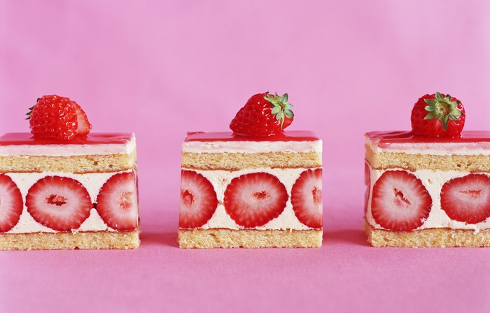 Three strawberry cakes on a pink background