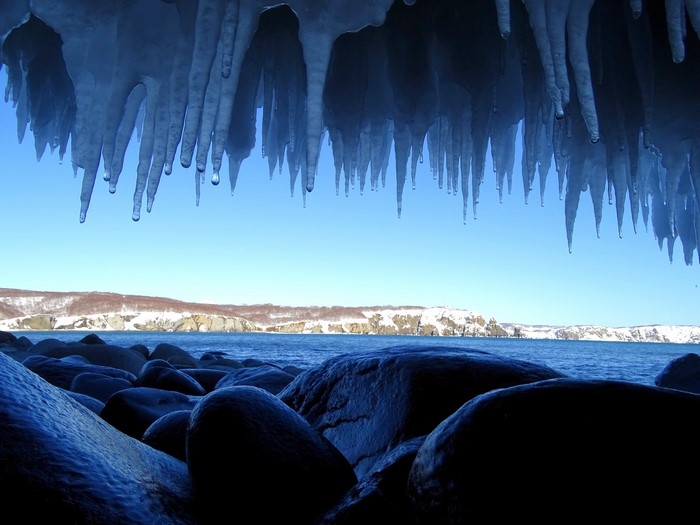Icicles hanging over a rocky shore and the sea