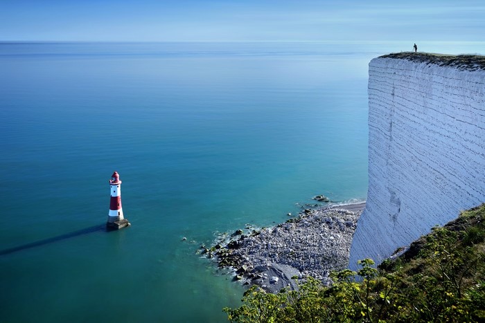 Lighthouse on the coast of England with a person on a cliff