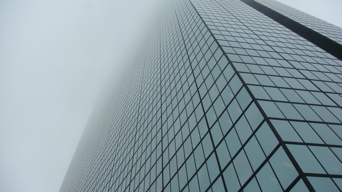 Low-angle view of a glass skyscraper in mist