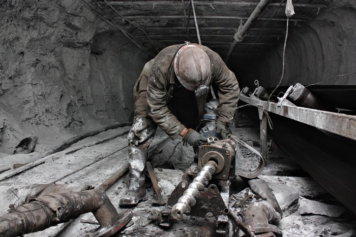 Miner operating a drill in a mine