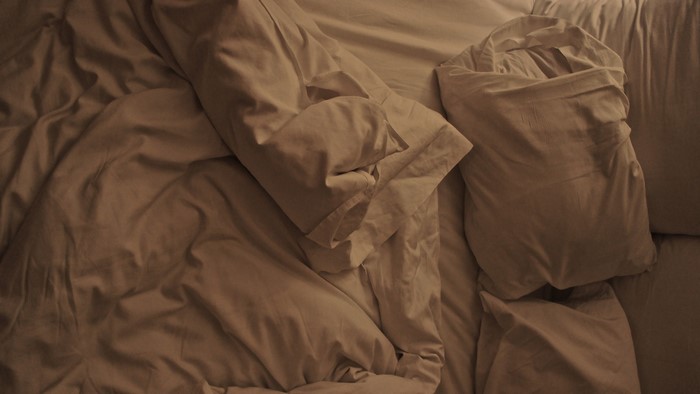 Unmade bed with pillows and blankets
