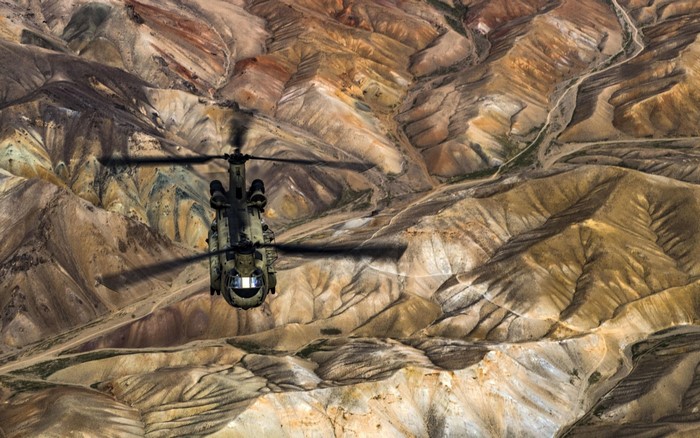 Boeing CH-47 Chinook helicopter flying over mountainous terrain