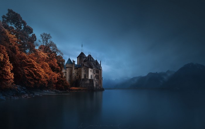 Castle on a lake with autumn trees and mountains
