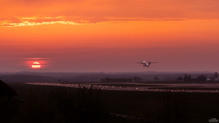 Airplane taking off at sunset over airport runway