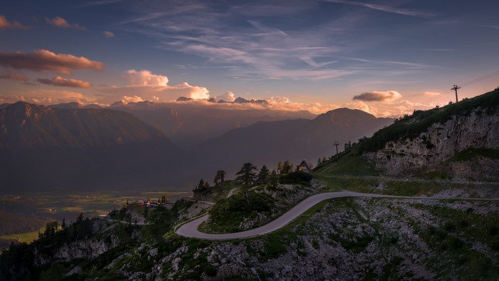 Winding mountain road at sunset with distant peaks