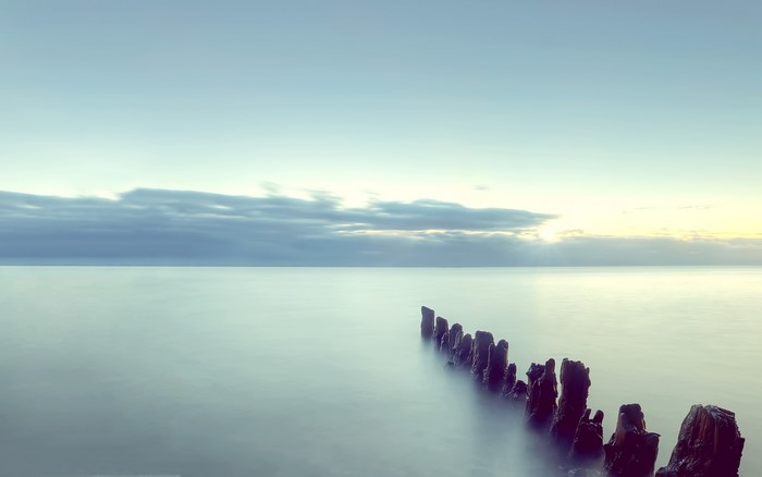 Sea and sky with wooden posts at horizon