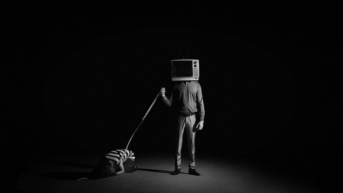 Man with TV head leading a person on a leash