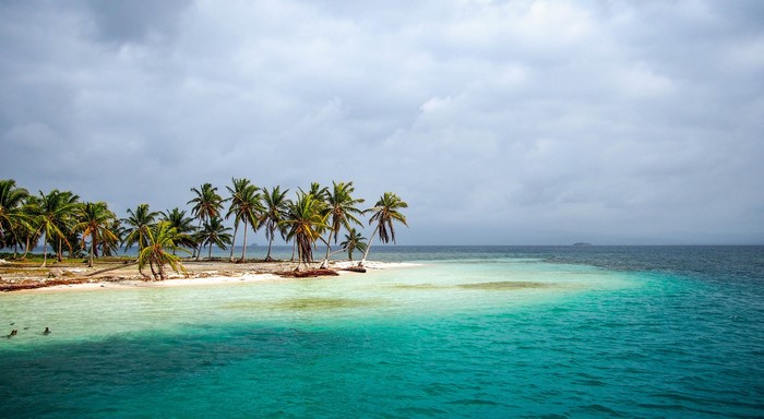 Tropical island with palm trees and turquoise sea under overcast sky