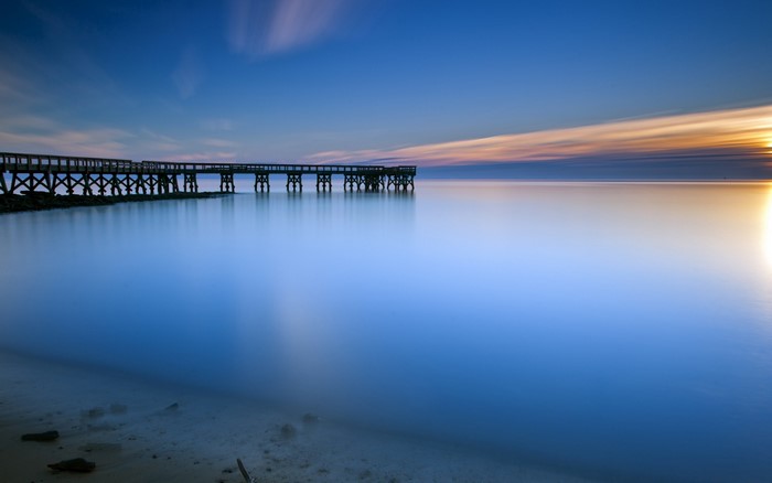 Long exposure of a pier at sunset over calm water