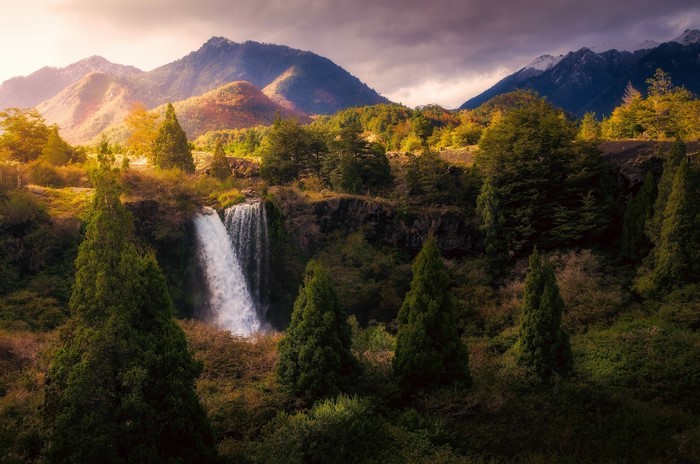 Waterfall cascading down a rocky cliff in a mountainous forest