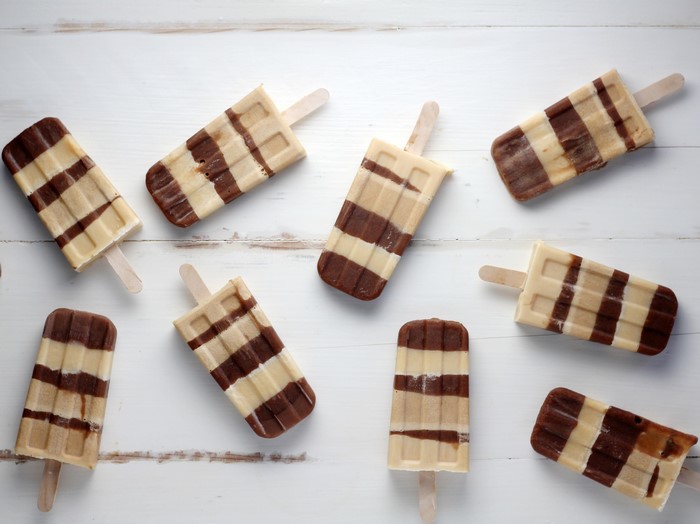 Chocolate and vanilla striped popsicles on white wood