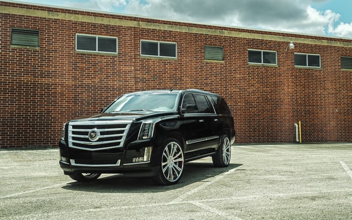 Black Cadillac Escalade parked in front of a brick building