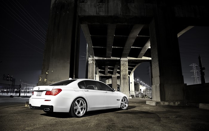 White BMW 7 Series car under a bridge at night